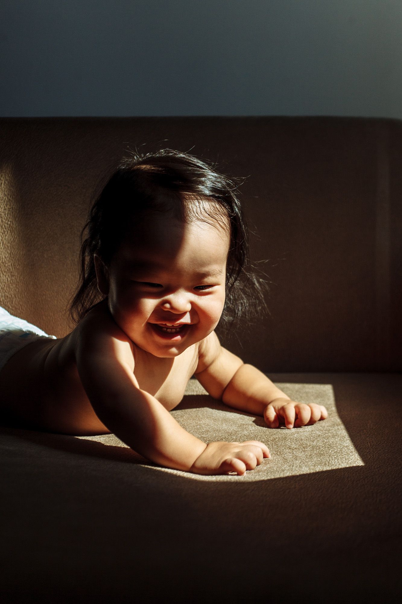 A series of moody low-key photographs showing small hands and feet emerging from dramatic shadows on a textured surface.