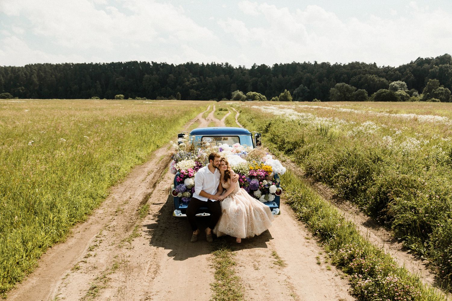 Seven panoramic views of a rural dirt road with vehicles and people gathering in a field.
