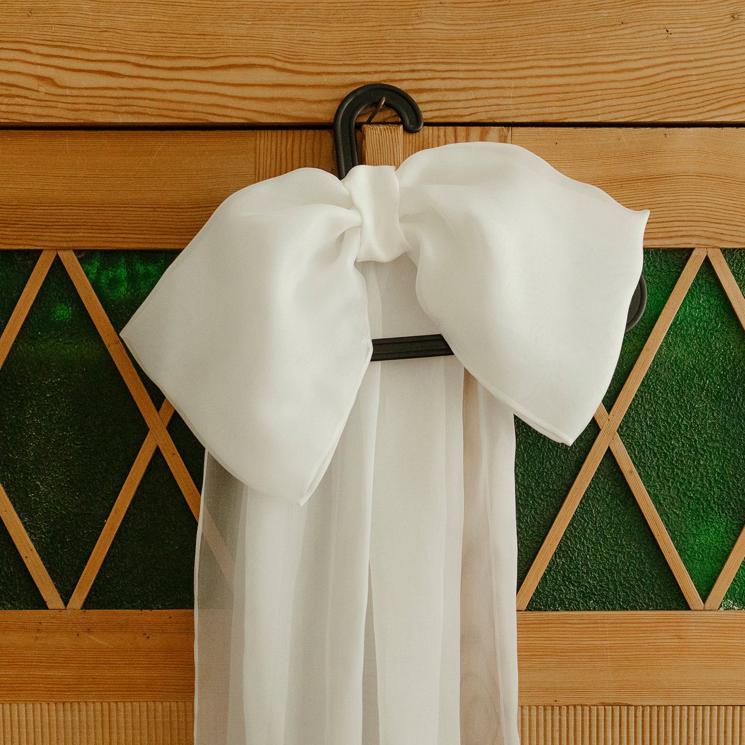 White paper napkin folded into an elegant bow shape against a wooden background with green decor.