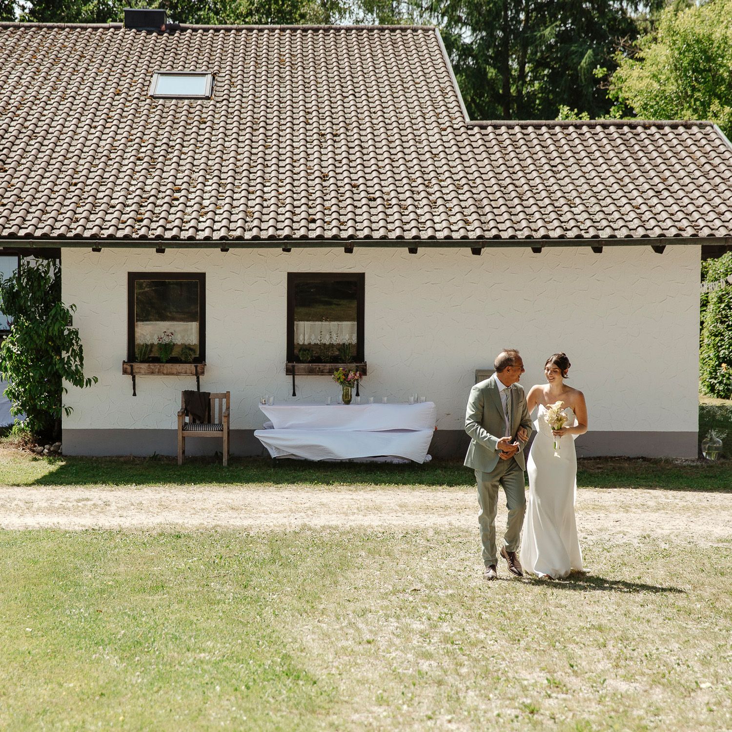 A couple shares a romantic moment in a rustic courtyard with white buildings and tiled roofs.