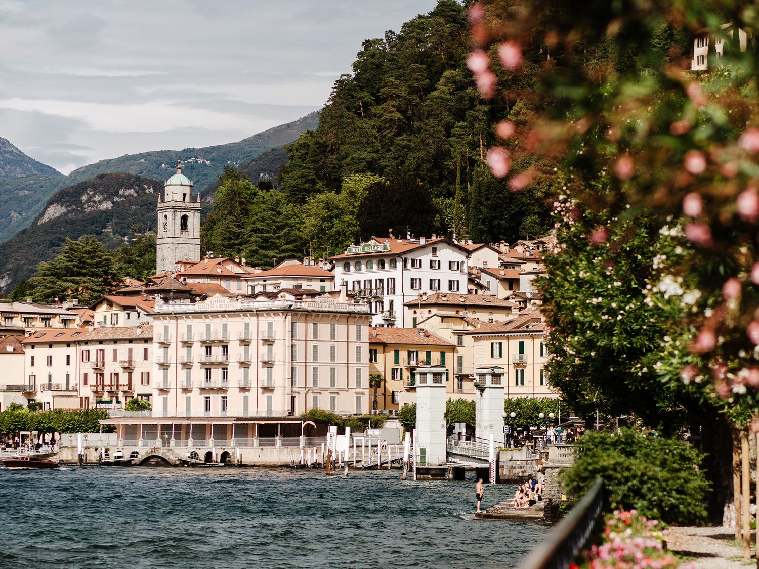 Scenic view of Bellagio village on Lake Como, Italy, with colorful buildings, a church tower, and lush green mountains.