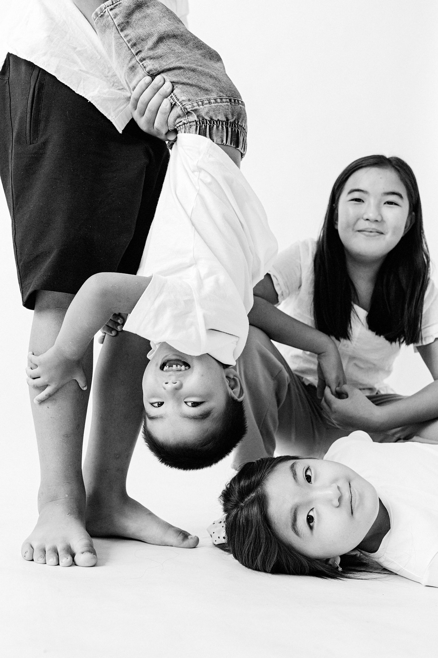 Creative black and white studio portrait showing playful poses against white background.