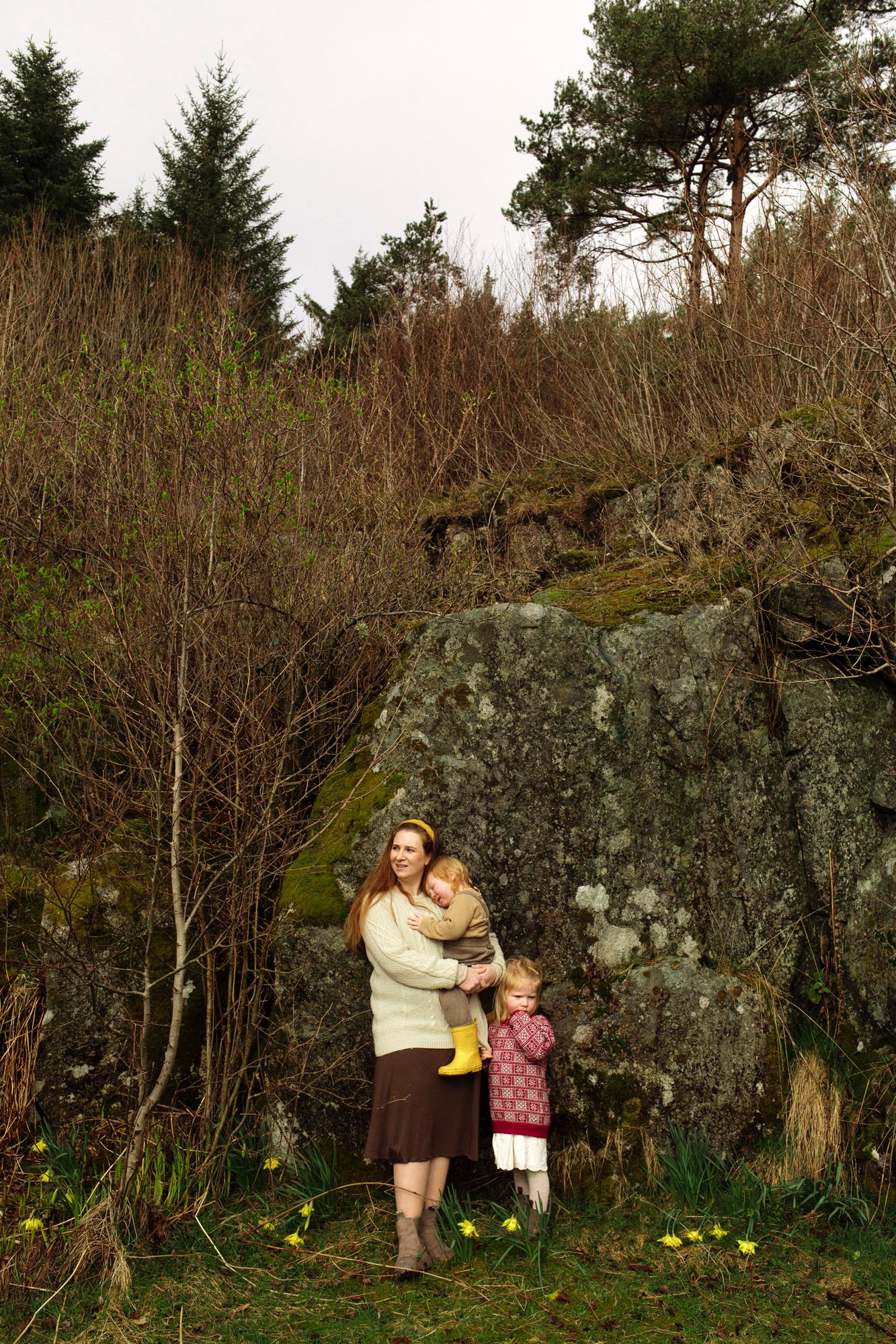 A scenic outdoor portrait against a large rock formation surrounded by evergreen trees.