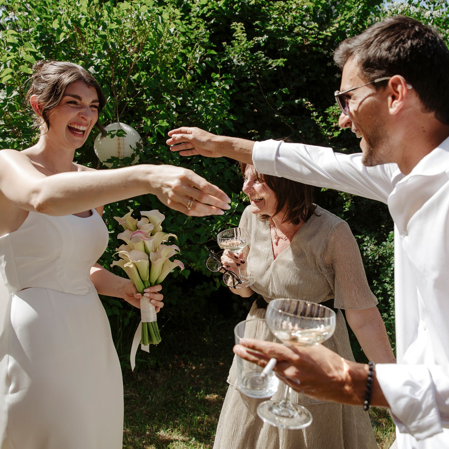 People celebrating and toasting with champagne glasses at an outdoor garden party on a sunny day.