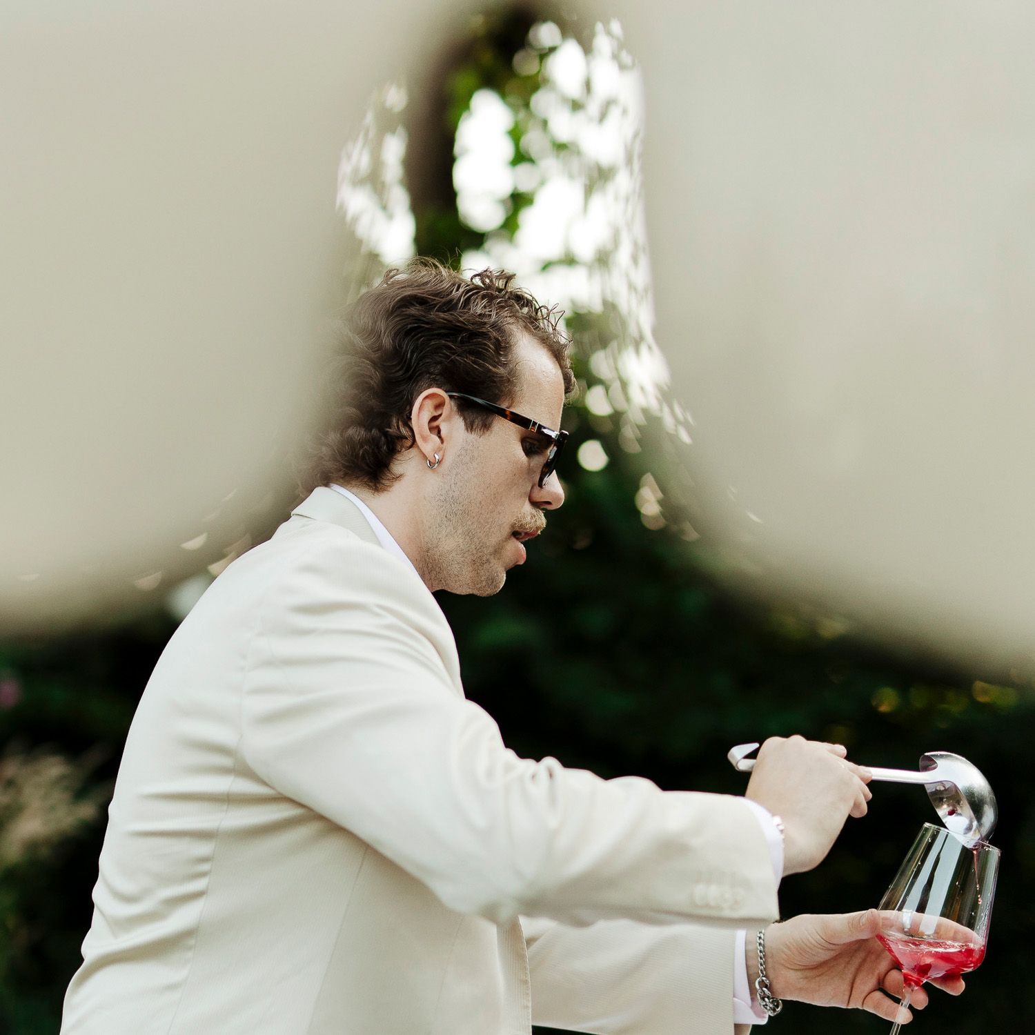 A person in a white lab coat pours liquid from a glass bottle into another container in a professional setting.