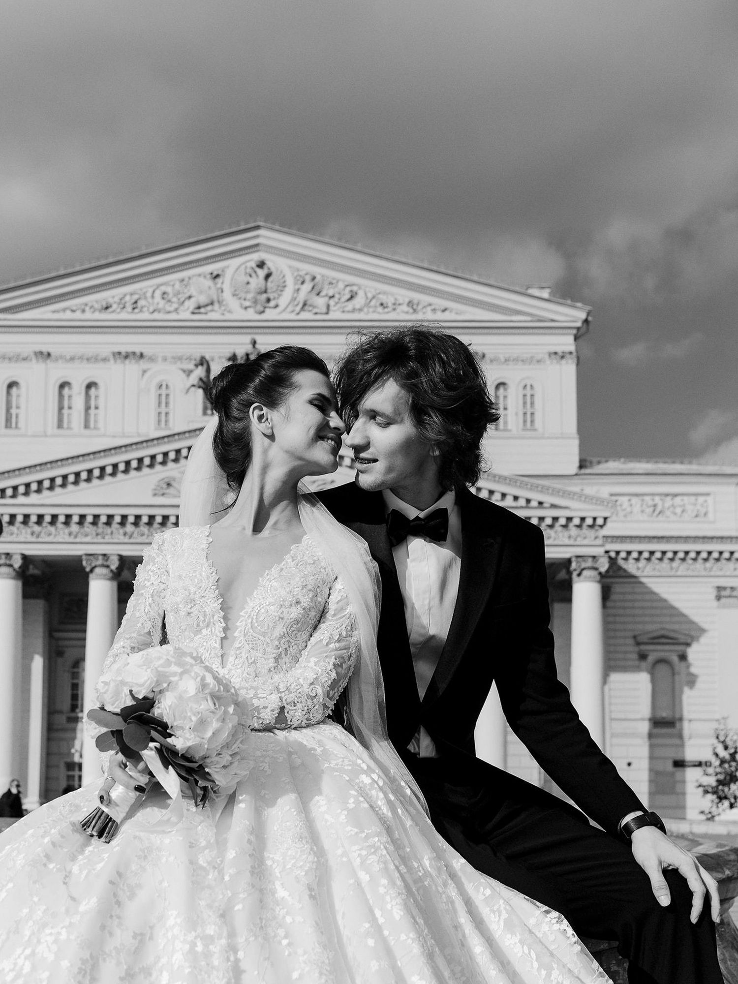 A romantic black and white wedding photo series showing a couple in formal attire embracing against a classical architecture backdrop.