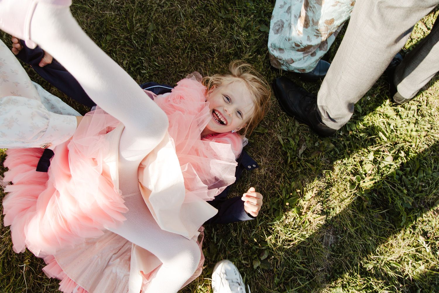 Wedding guests celebrating on grass with pink and white decorative elements.