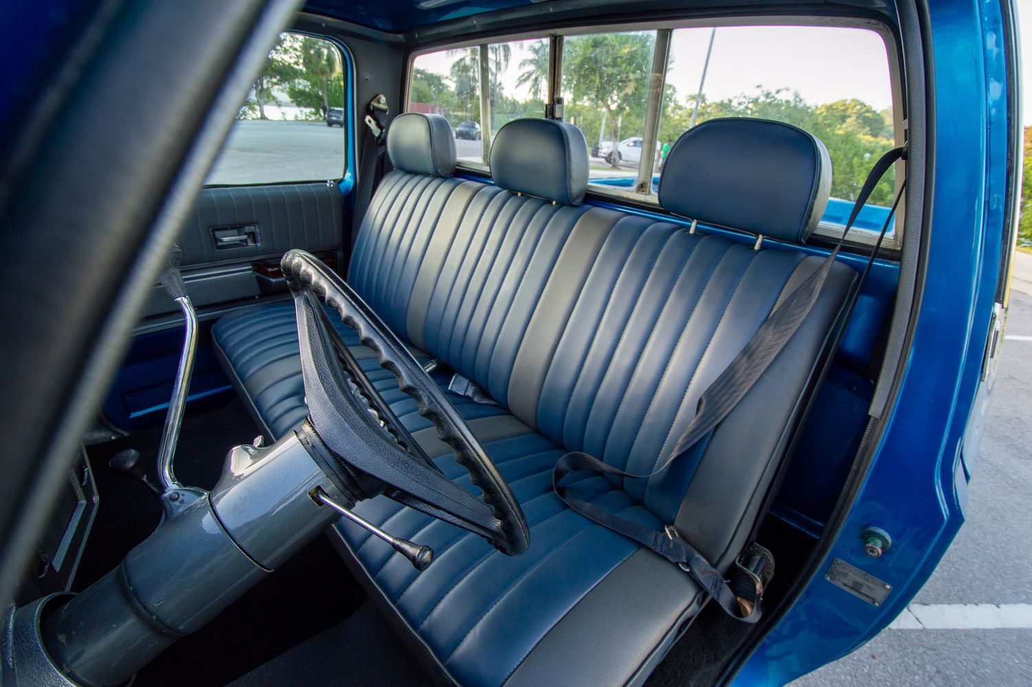Blue vintage truck interior showing a black bench seat and steering wheel, classic retro design in excellent condition.