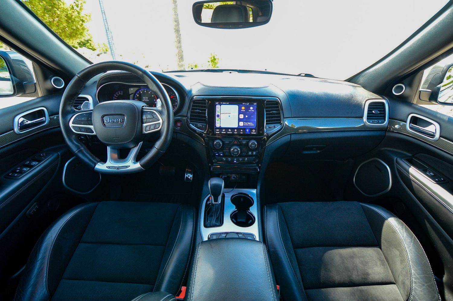 Interior view of a Jeep Grand Cherokee featuring leather seats, touchscreen infotainment, and dual-zone climate controls.
