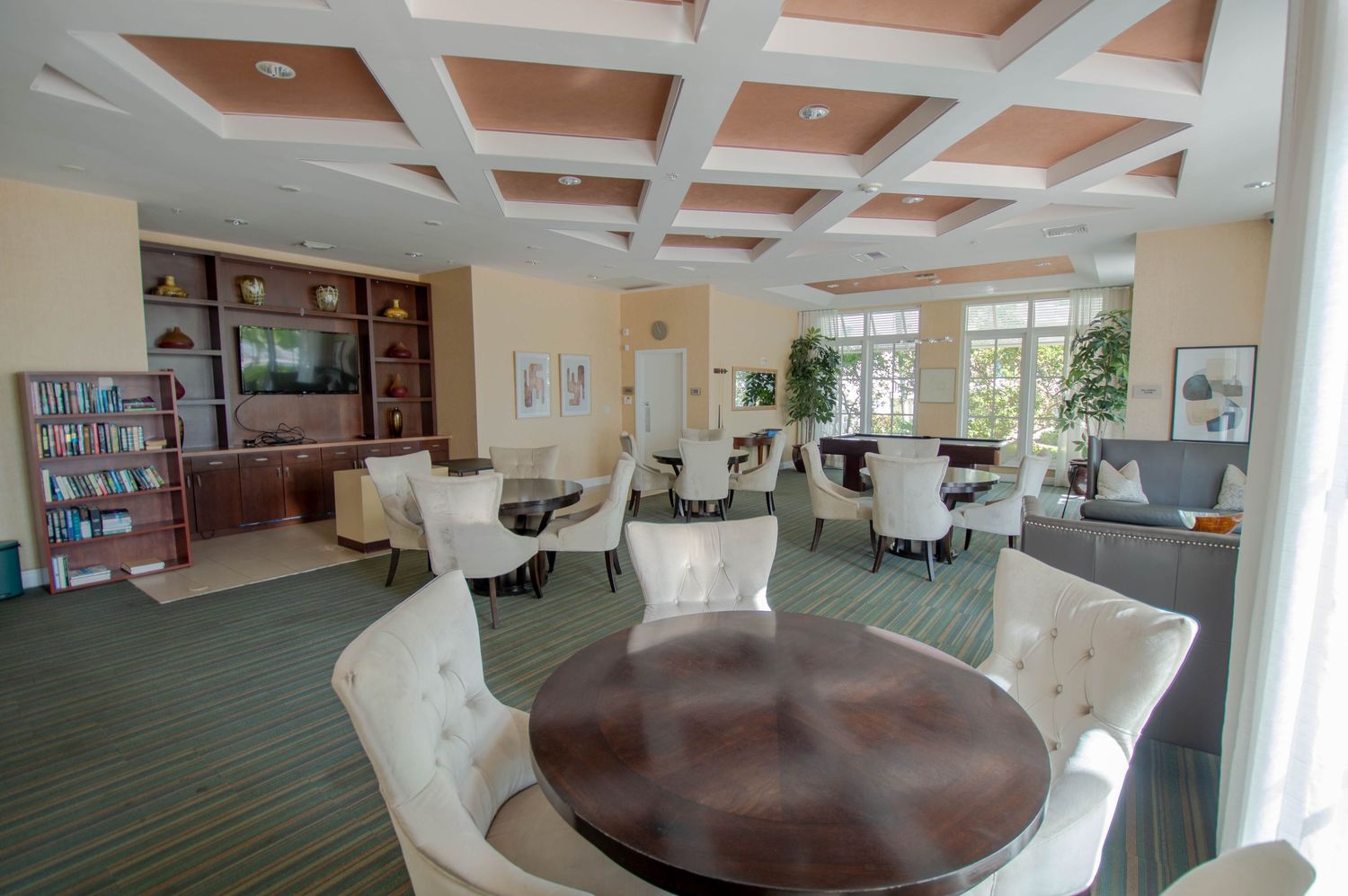 Elegant community room with coffered ceiling and comfortable seating arrangements.
