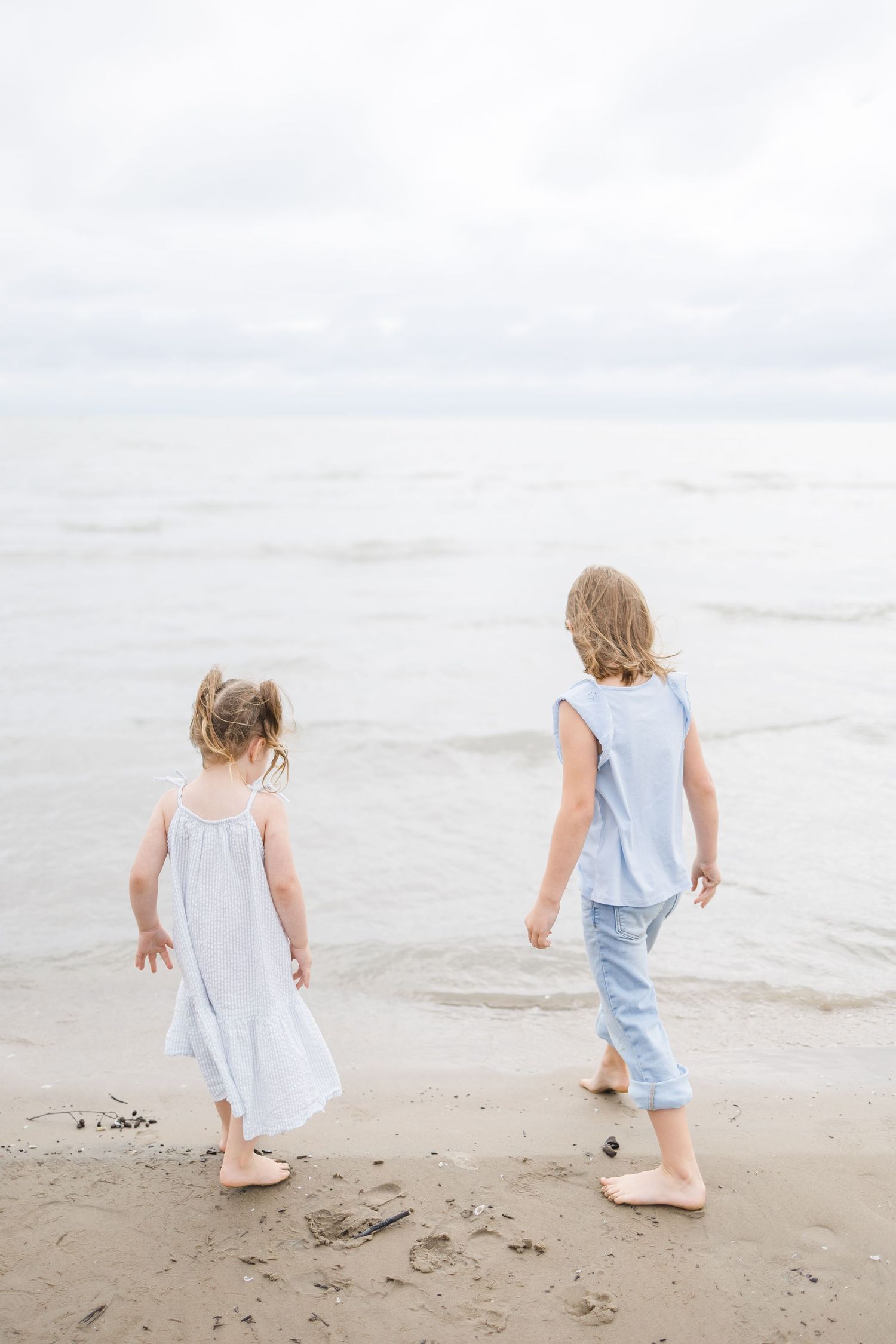 Two small children exploring a peaceful beach shoreline at sunset.
