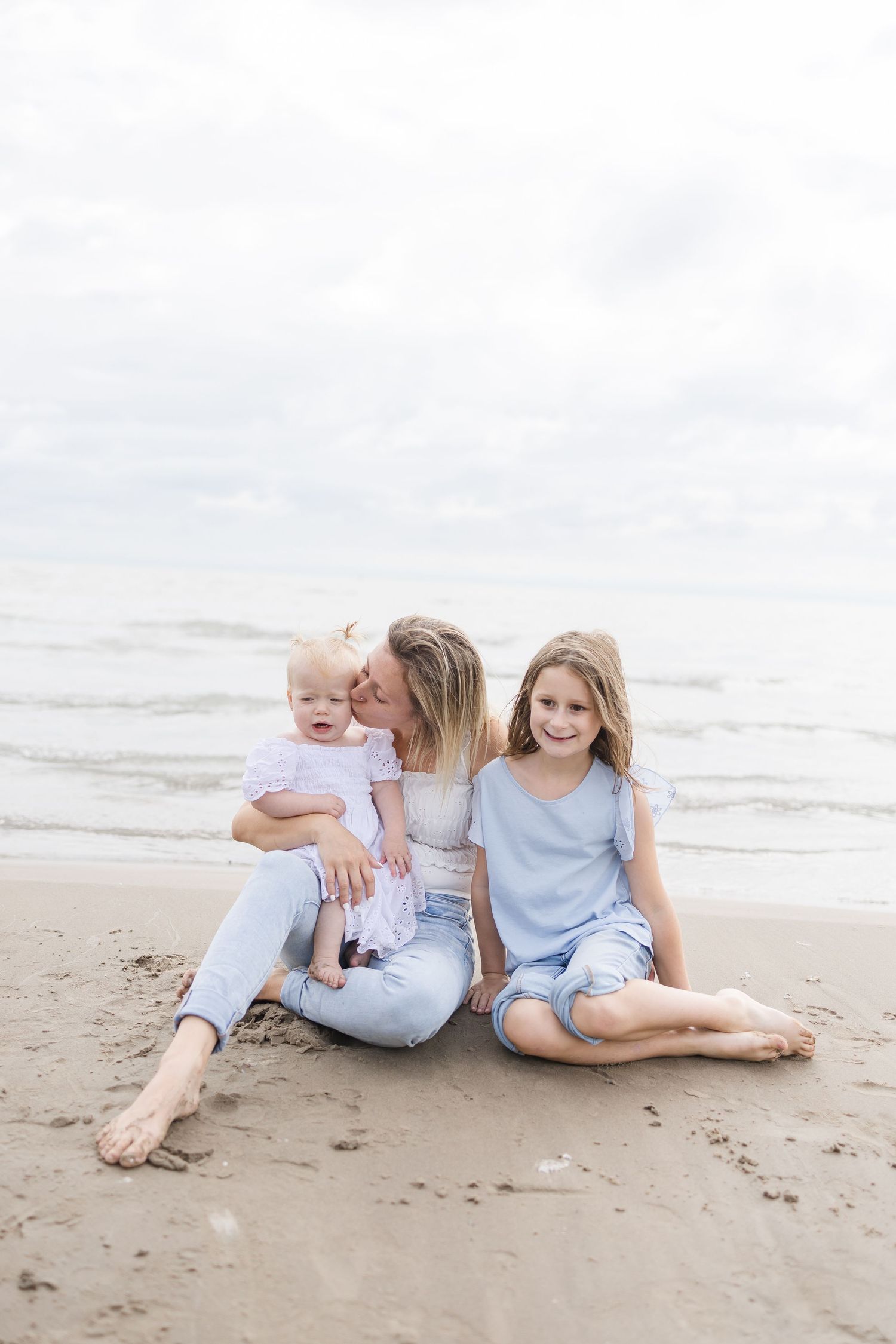 Family relaxing together on a serene beach during an overcast day.