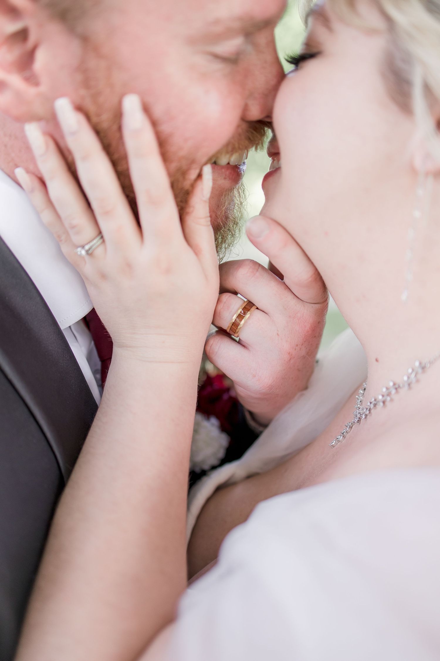 Close-up of wedding rings and tender moment between newlyweds.