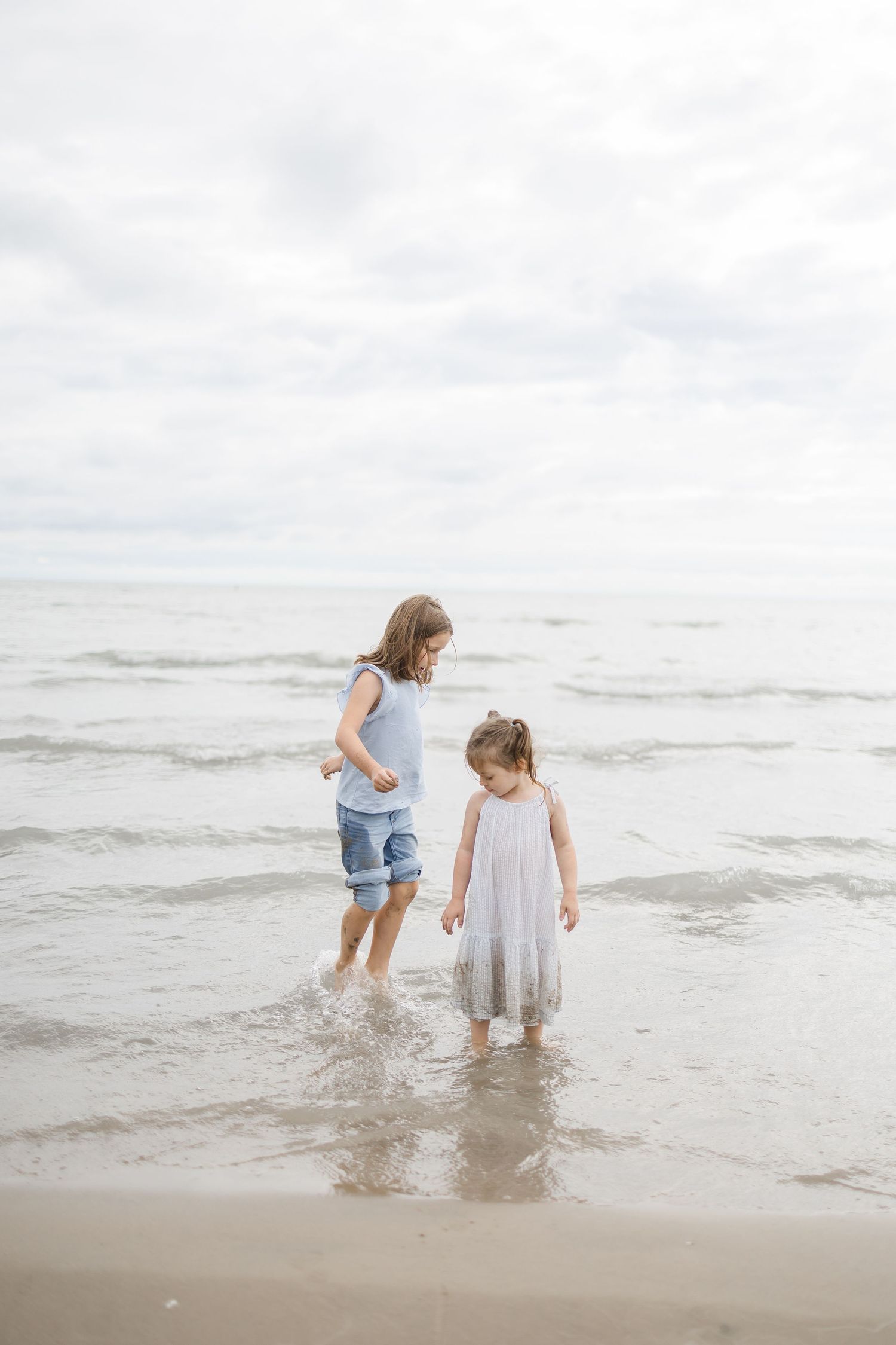 Children playing and splashing in shallow ocean water at the beach.