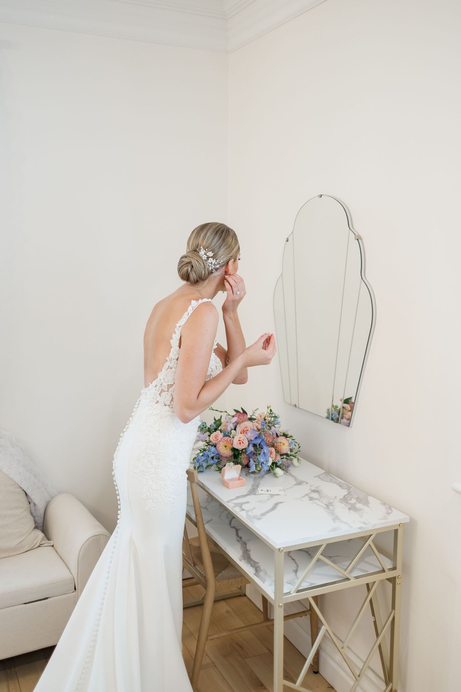 White wedding dress details being photographed at a vanity table with floral accents.