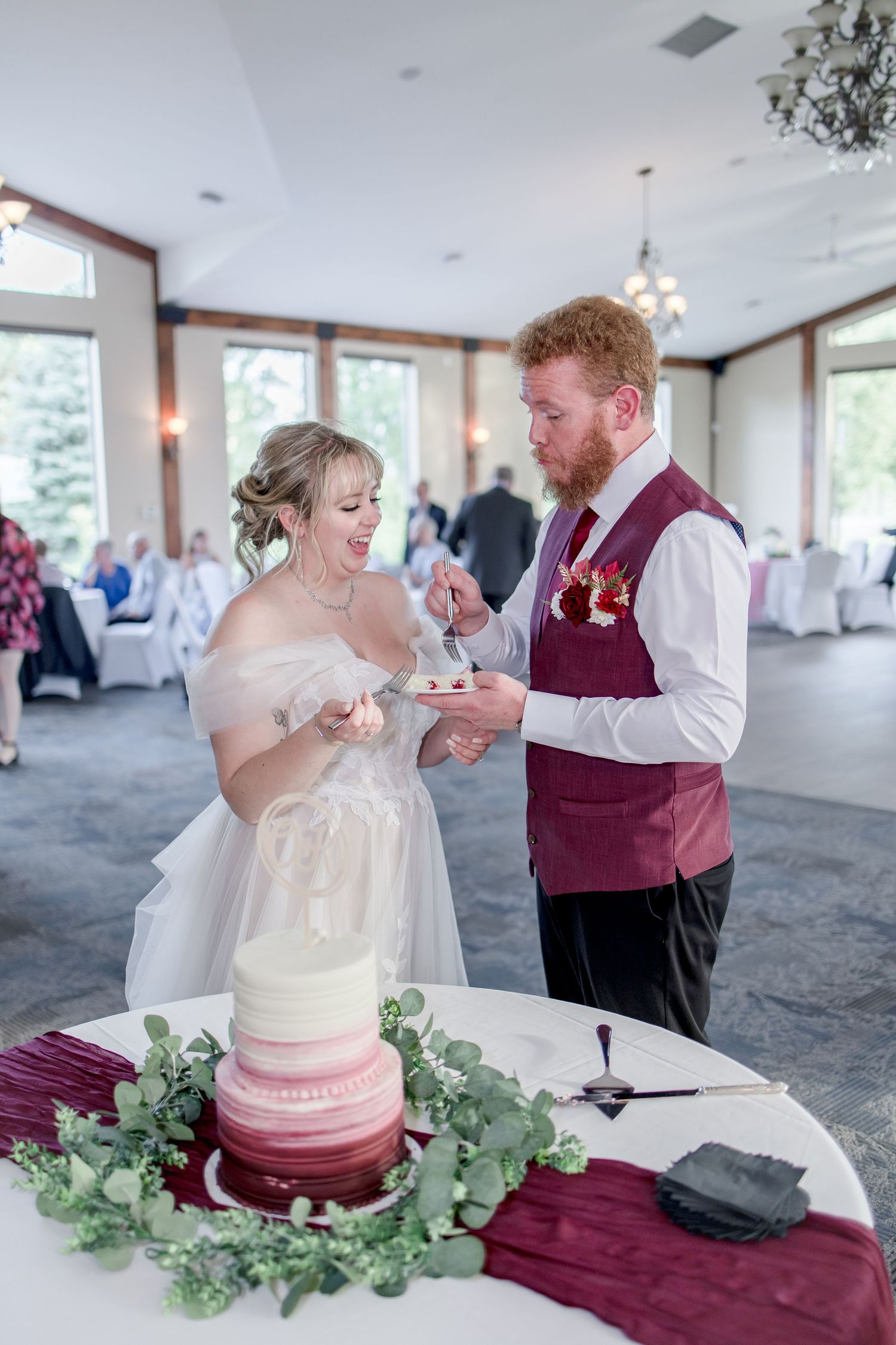 Newlyweds feeding each other wedding cake during traditional cake cutting ceremony.