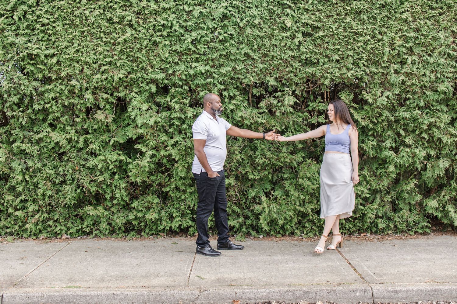 Two people walking along a lush garden path holding hands.
