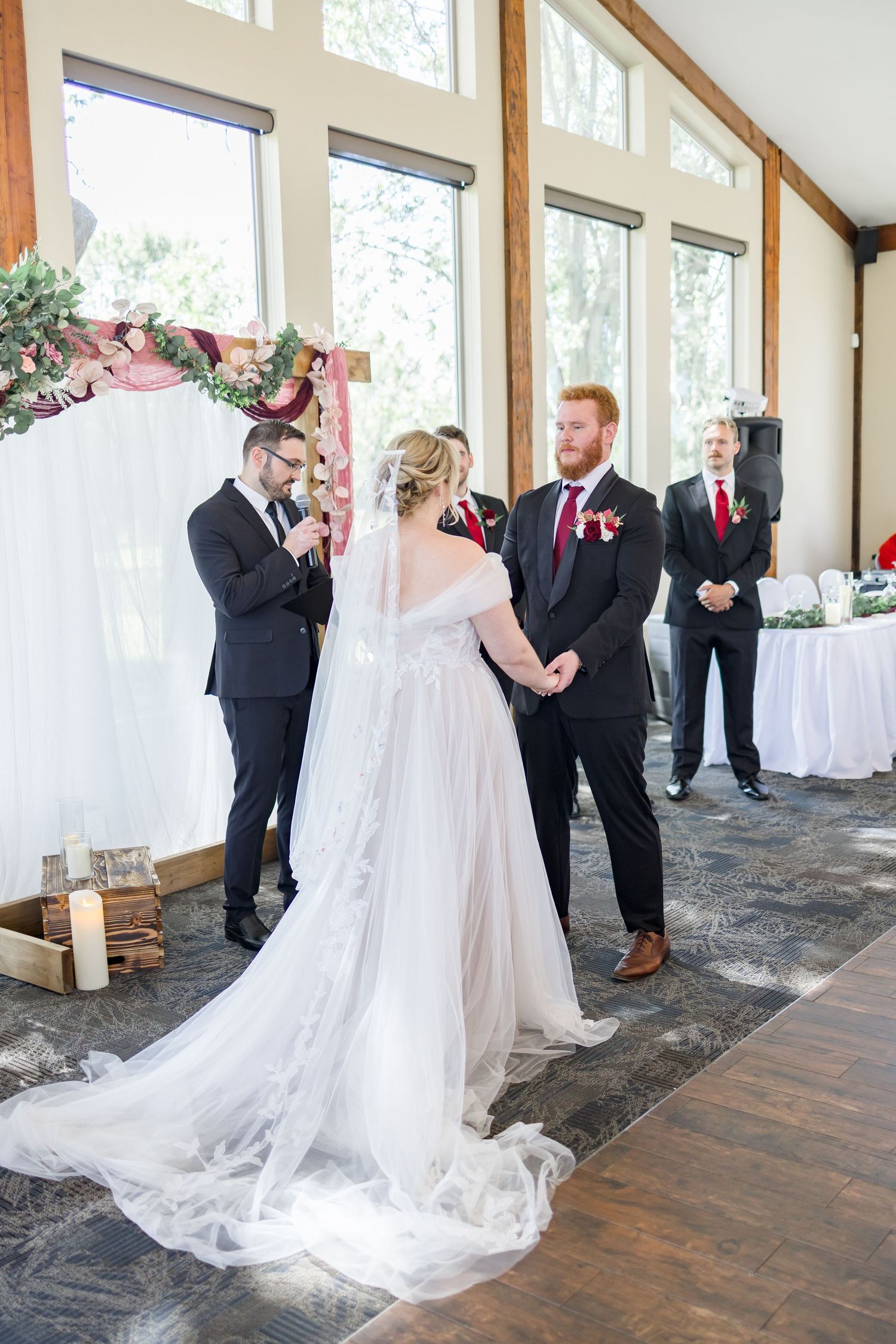 Wedding couple shares first look moment in a bright indoor venue with wooden beams and white decor.