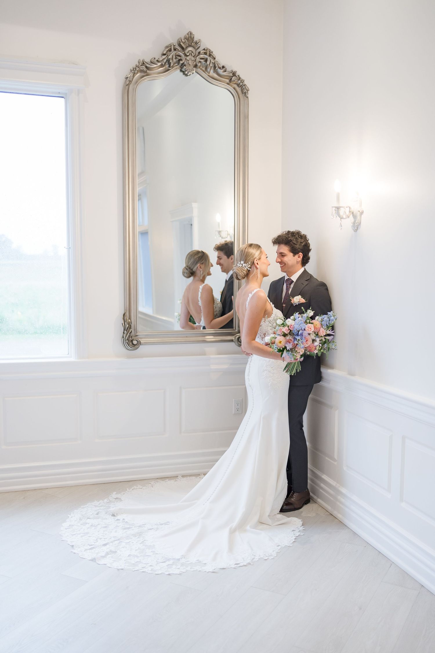 Elegant white bridal room with ornate mirror and wainscoting details.