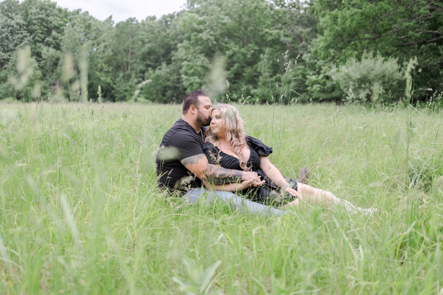 Couple relaxing in a sunny meadow surrounded by summer greenery.