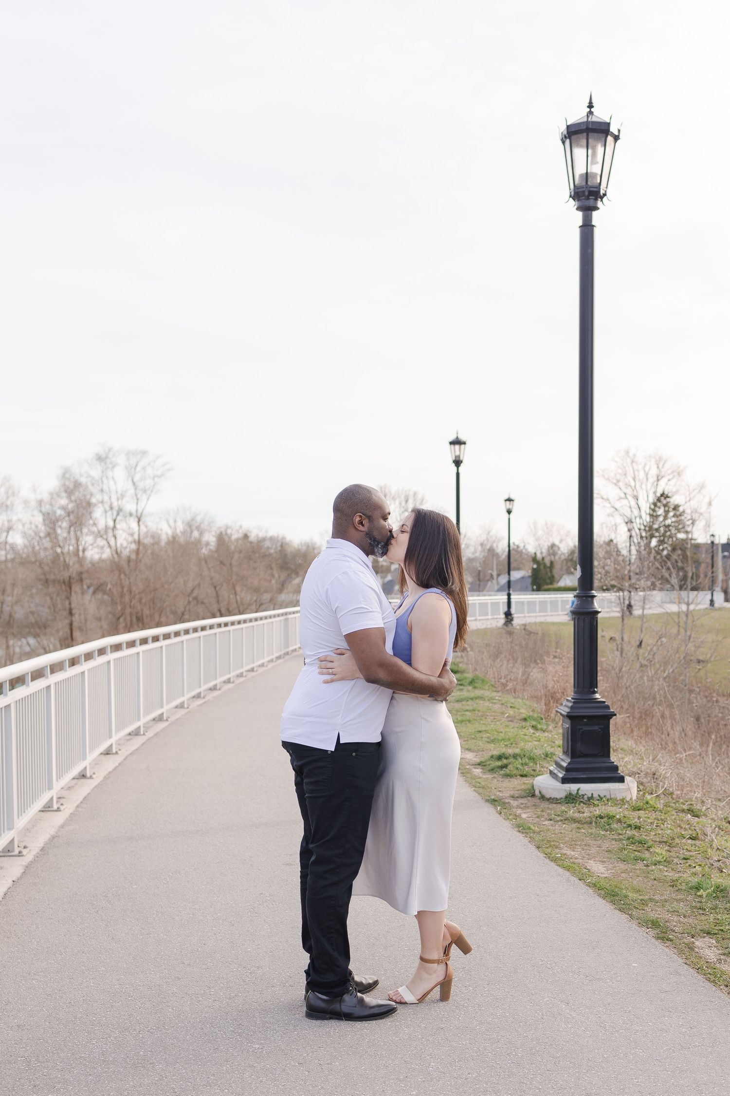 Couple sharing romantic moment on path with vintage lampposts.