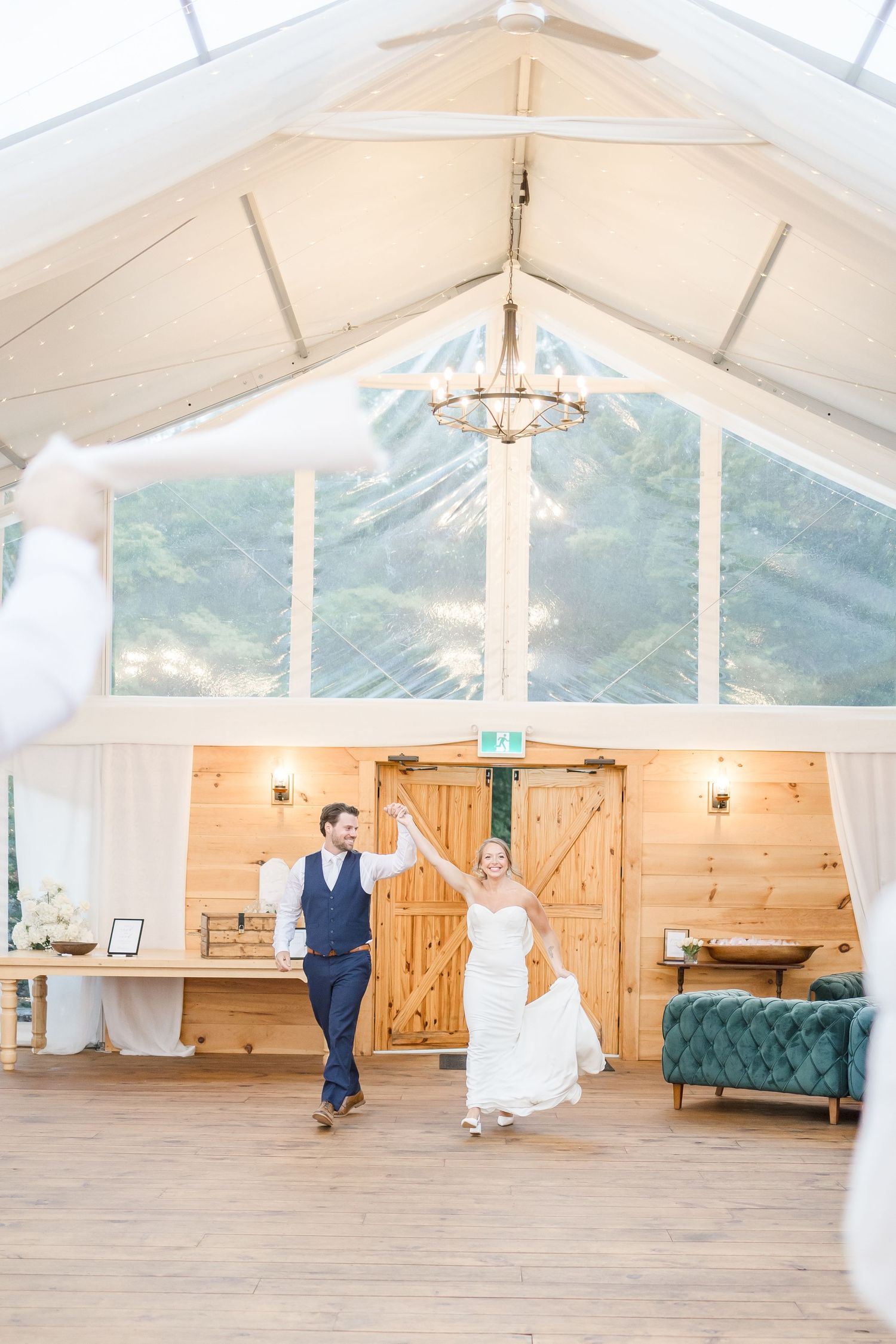 Spacious white tent wedding venue with wooden walls and elegant furnishings.