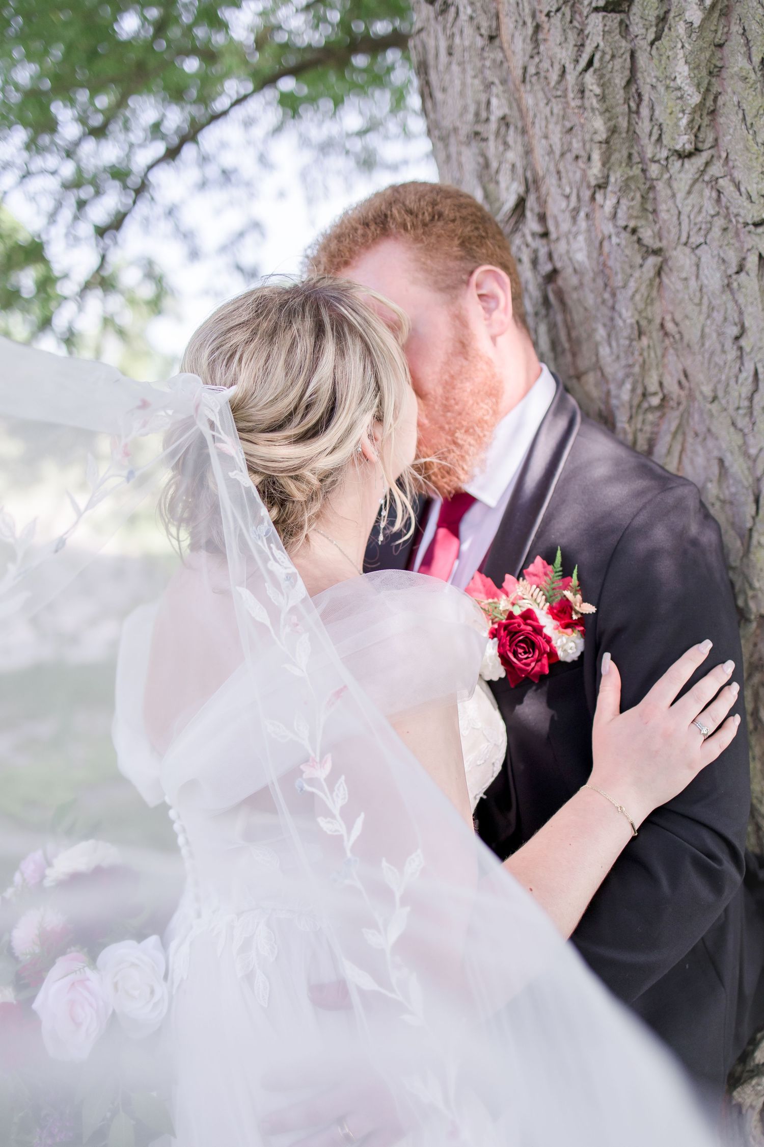 Intimate wedding portrait moment captured through delicate veil outdoors.