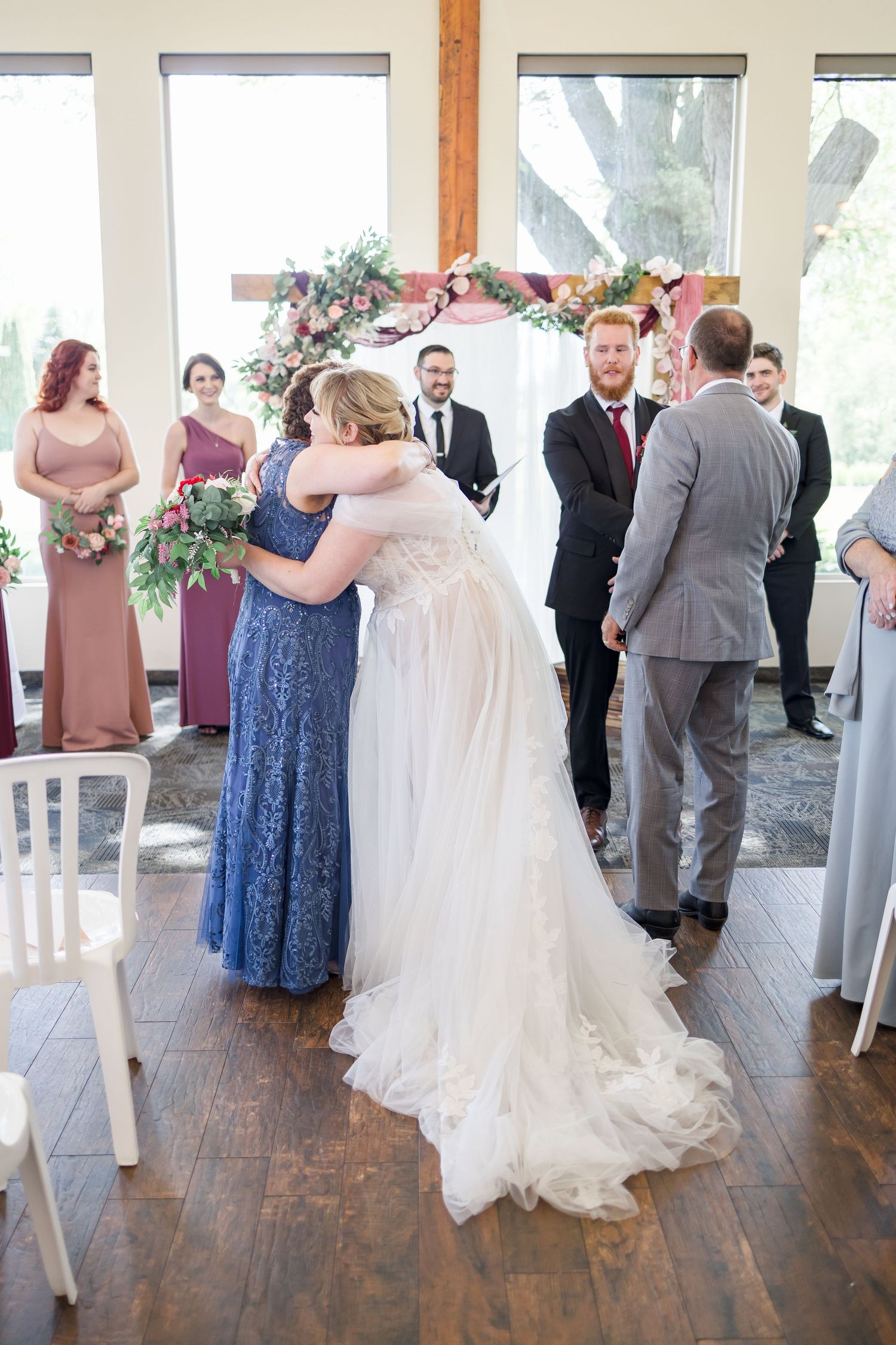 Wedding celebration with guests dancing in a bright venue with hardwood floors and white decor.