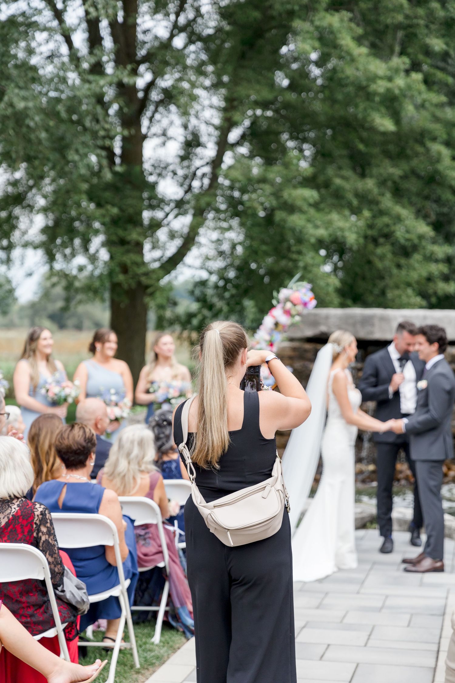 A photographer documents a wedding ceremony from the aisle with guests seated on either side.