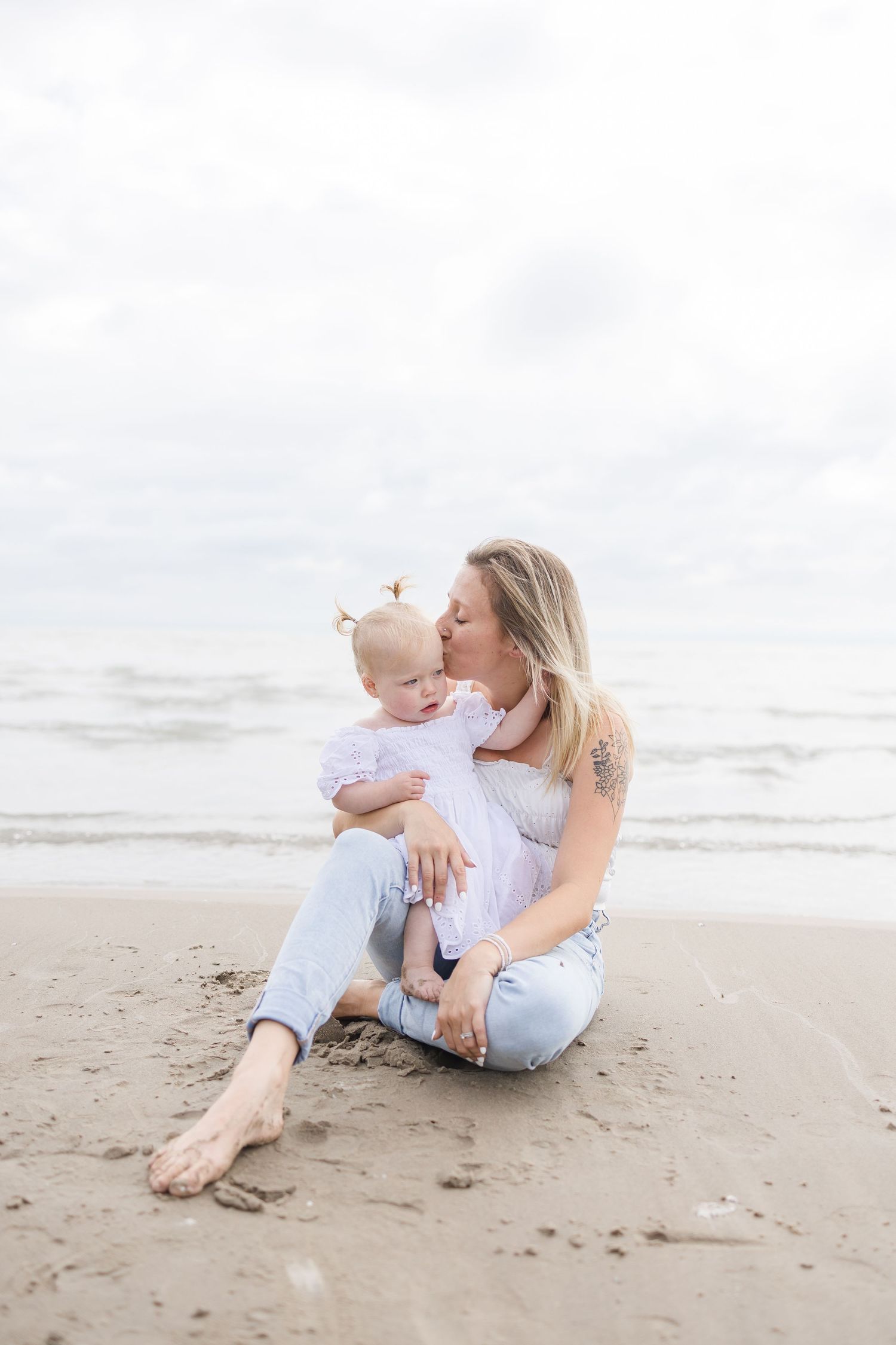 Parent and baby sharing an intimate moment while sitting on the beach.