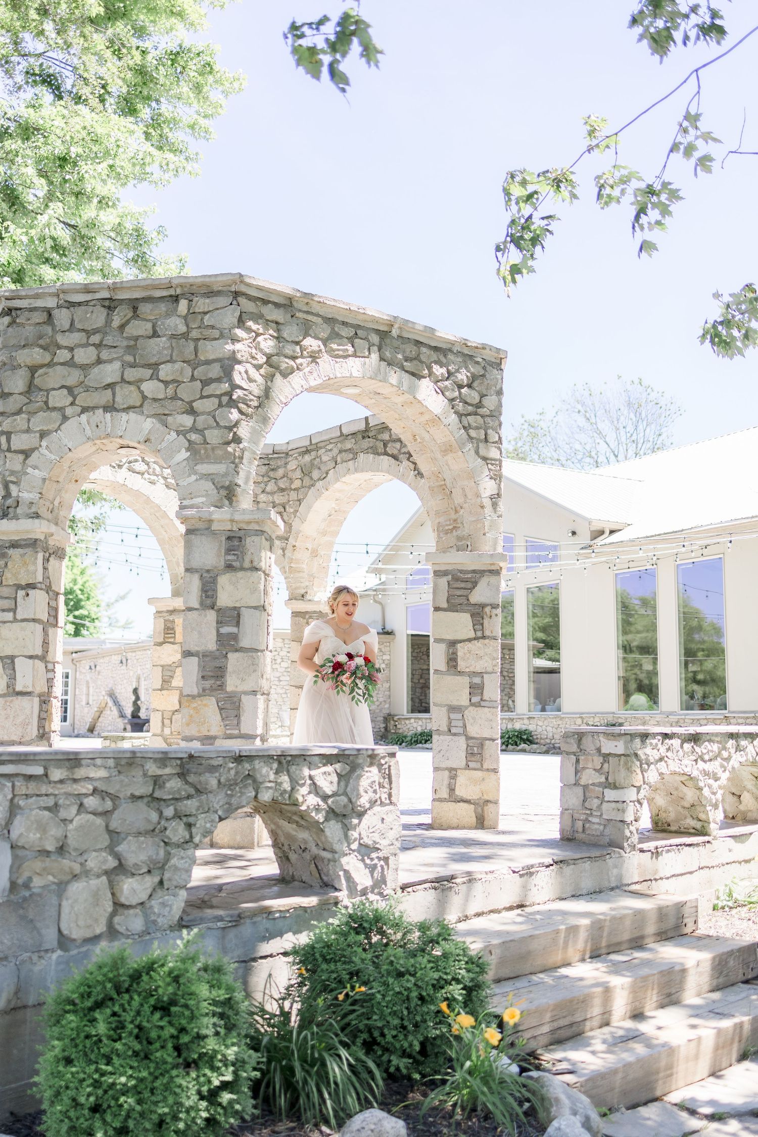 Stone archways decorated with floral arrangements in an outdoor wedding venue.