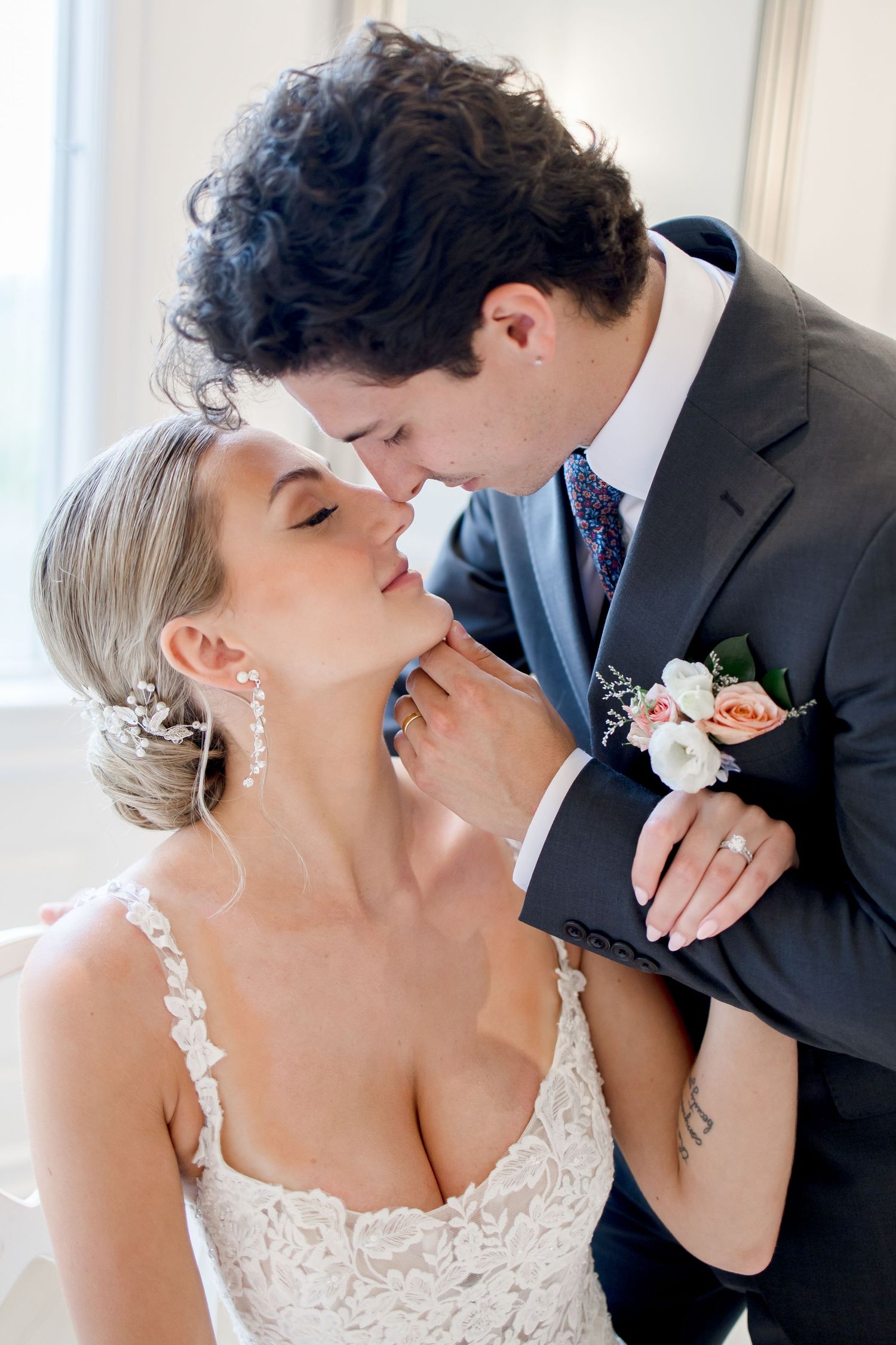 Intimate wedding couple moment captured in a bright white room.