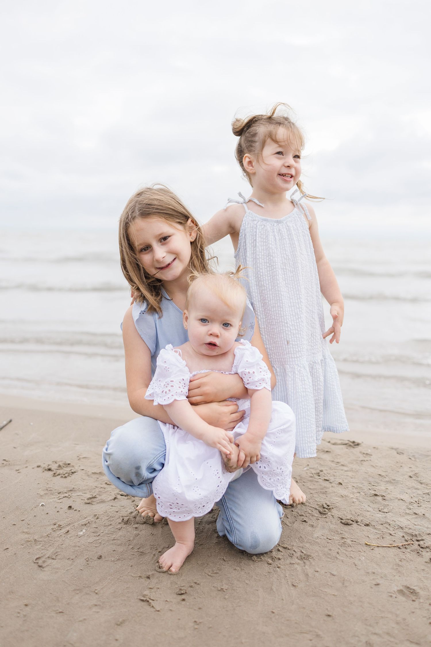 Children playing on sandy beach wearing casual summer outfits.