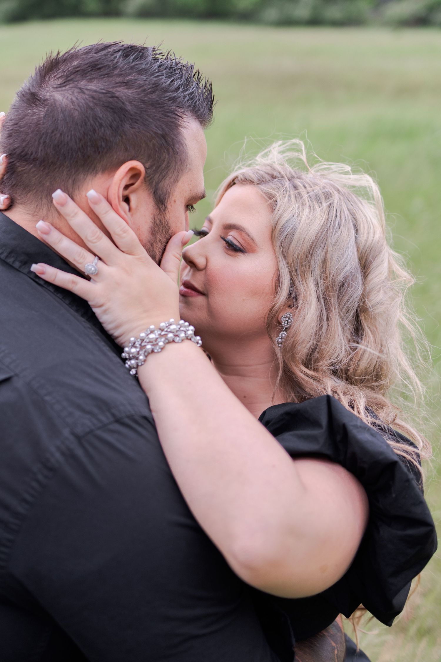 A tender embrace between a couple sharing a romantic kiss in an outdoor field.