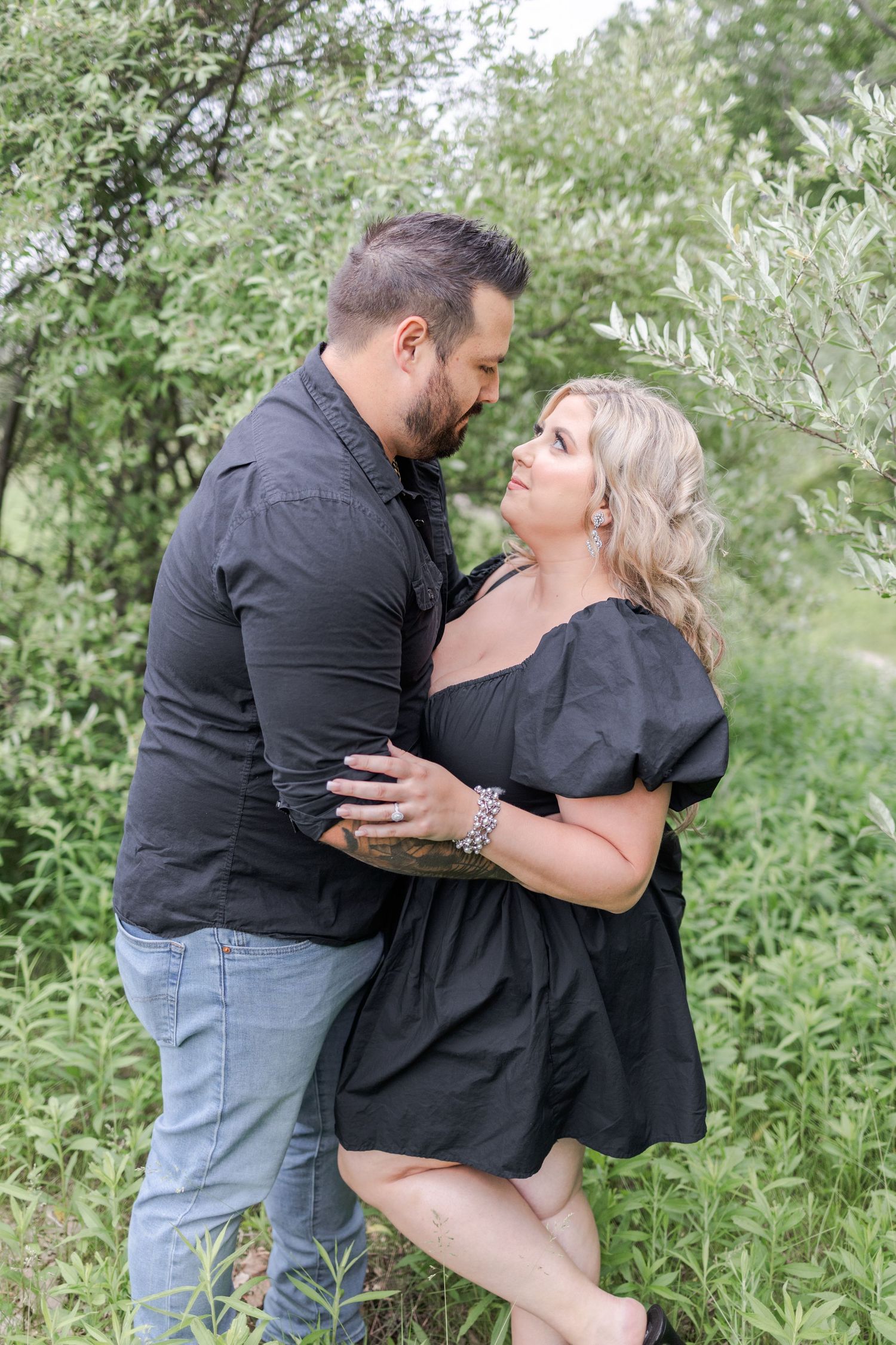 A tender embrace photographed in a natural outdoor setting with green foliage.