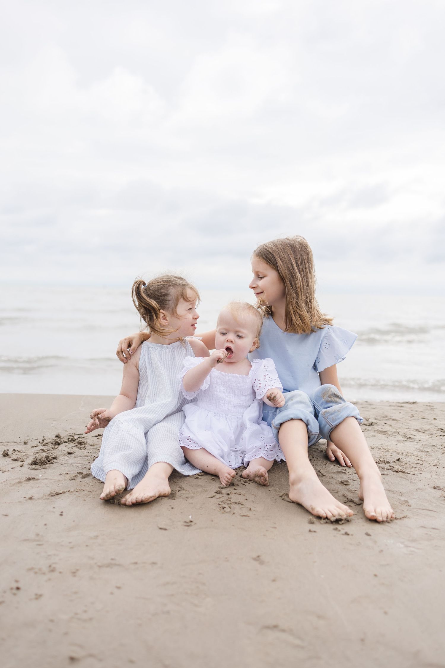 Family members lounging on beach sand wearing coordinated blue and white outfits.