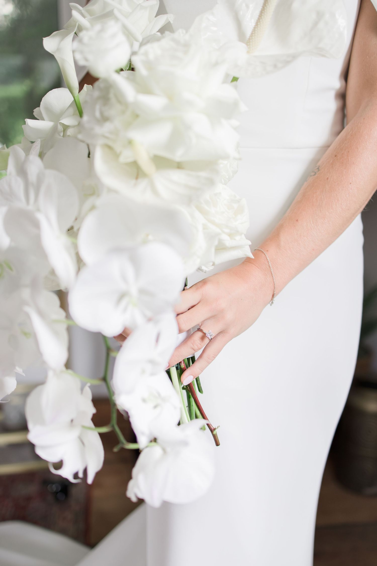 Elegant white bridal bouquet details showing flowers and the bride's wedding ring.