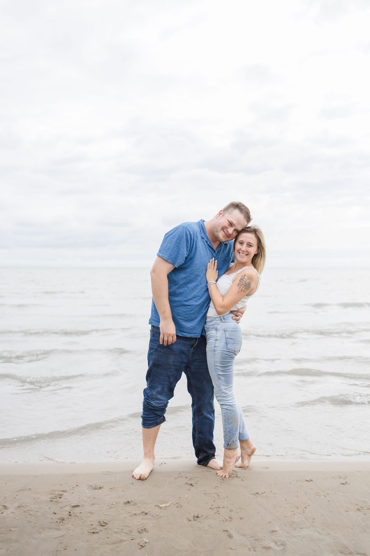 Couple enjoying a playful moment together on a cloudy beach.