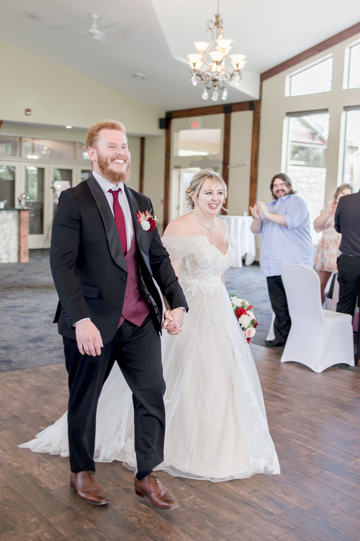 Wedding celebration in an elegant indoor venue with hardwood floors and crystal chandeliers.