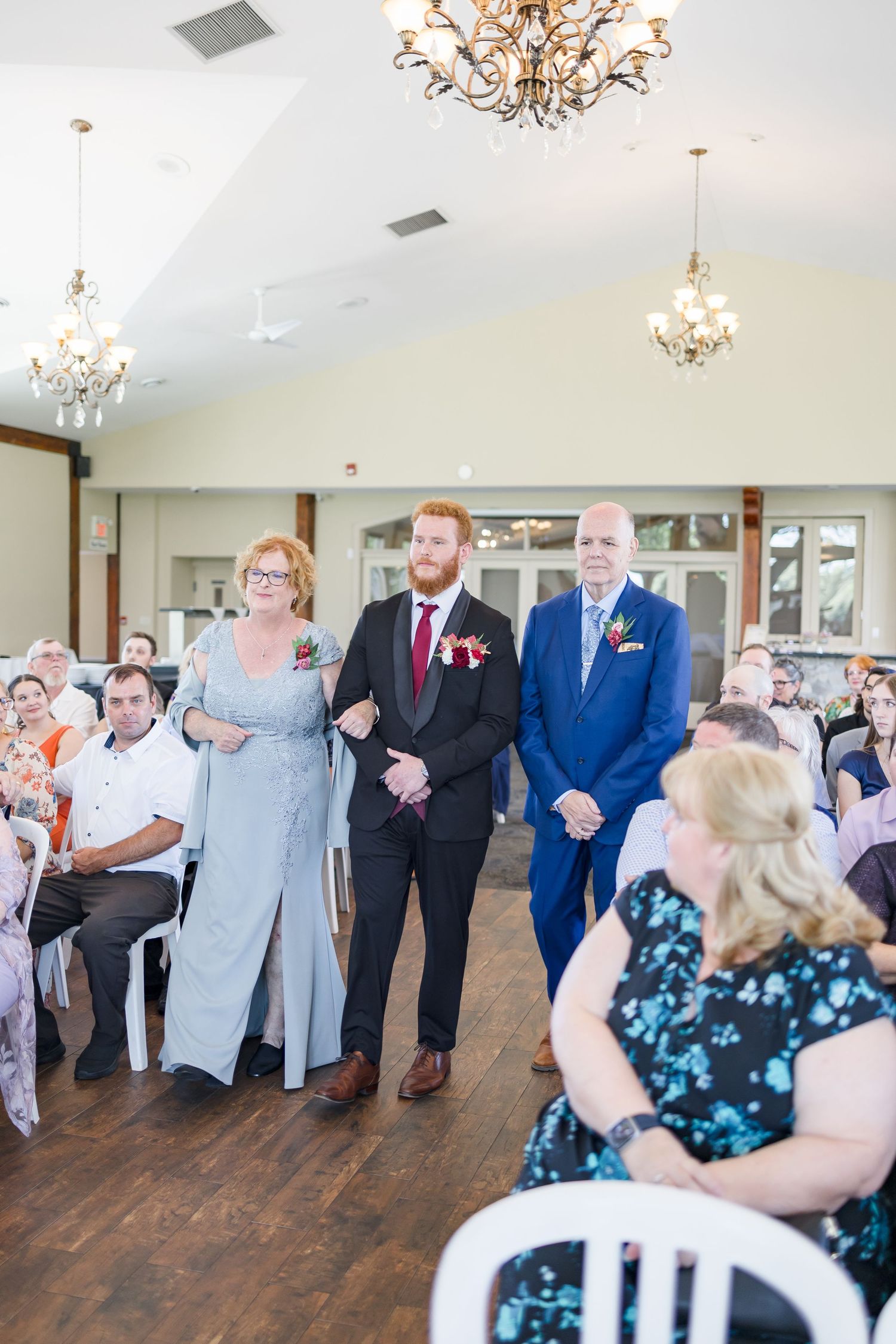 Wedding guests dance and celebrate in an elegant reception hall with chandeliers.