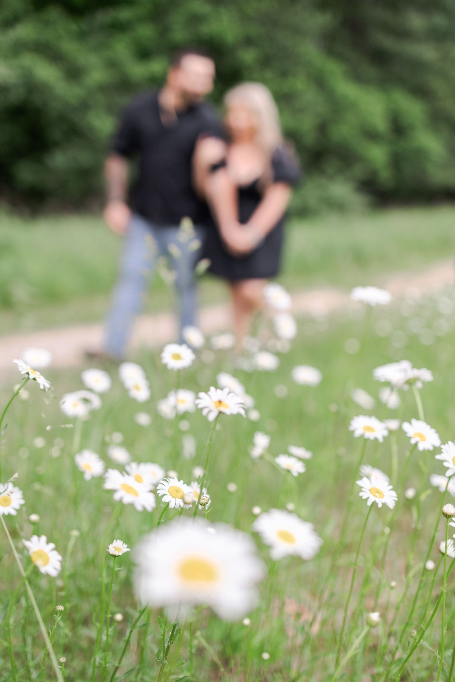 Wildflowers bloom in foreground with soft focus figures in a green meadow.