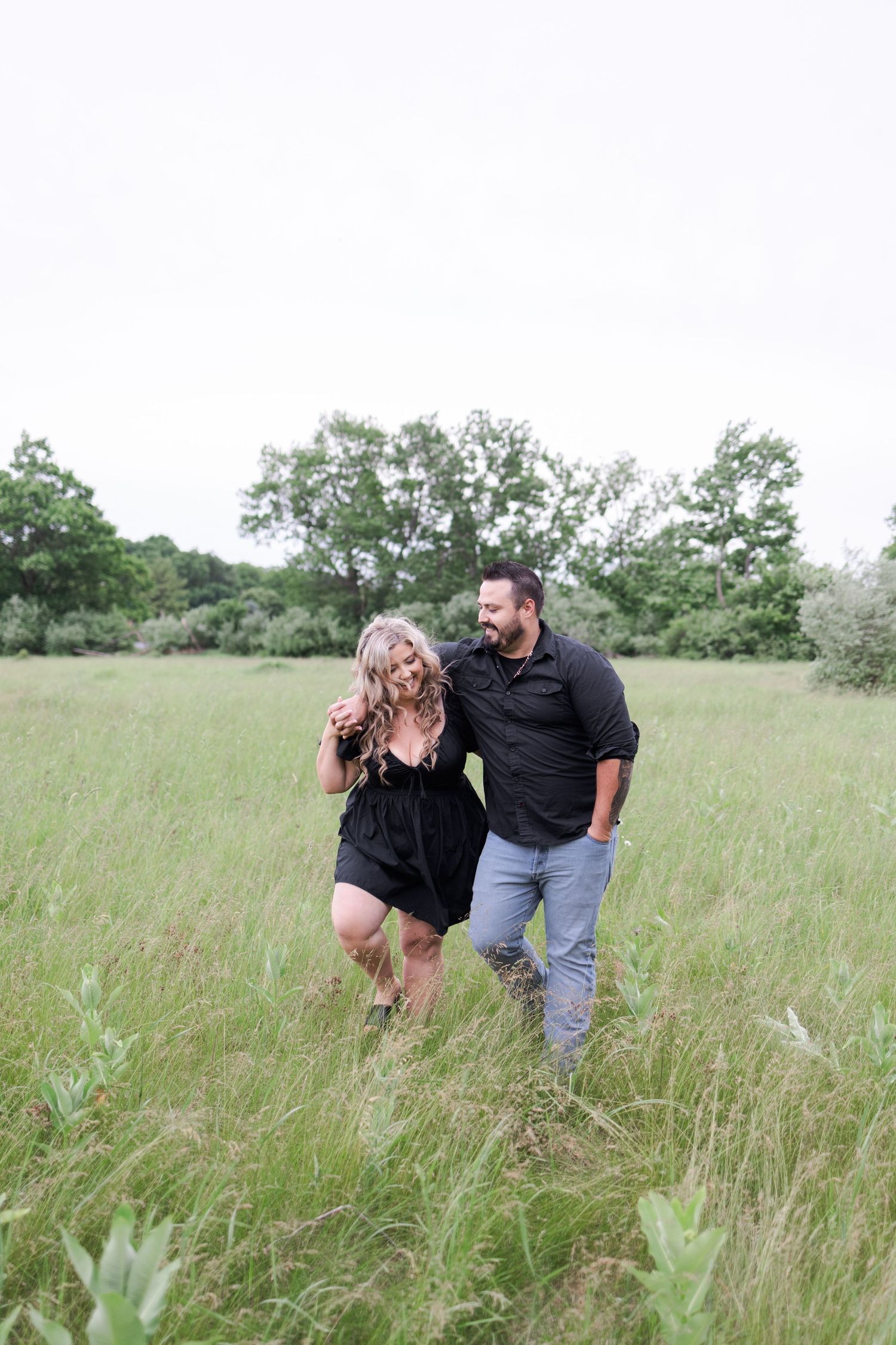 A couple shares a playful moment in a field of tall grass.