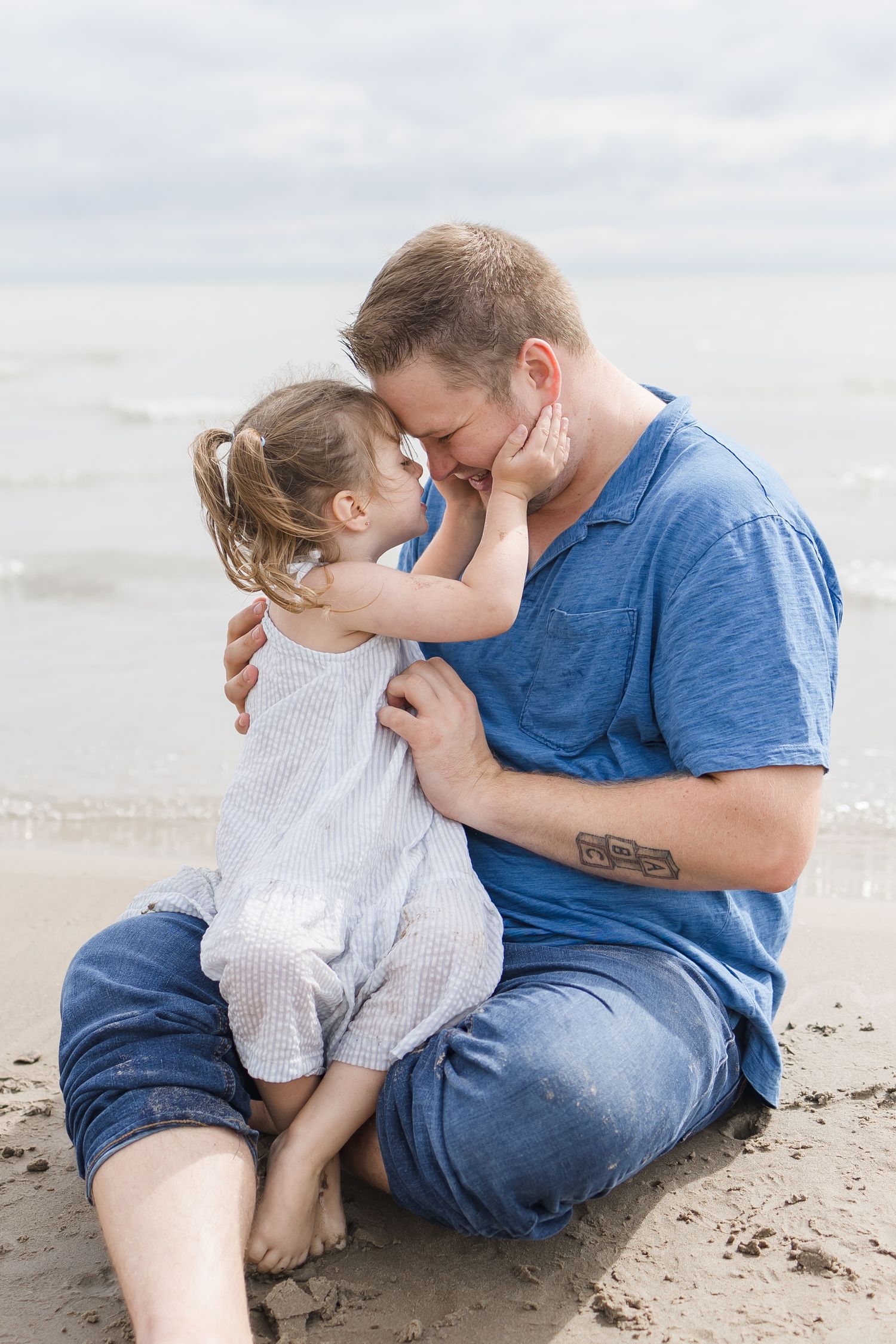 A tender moment shared between parent and child sitting together on a sandy beach.