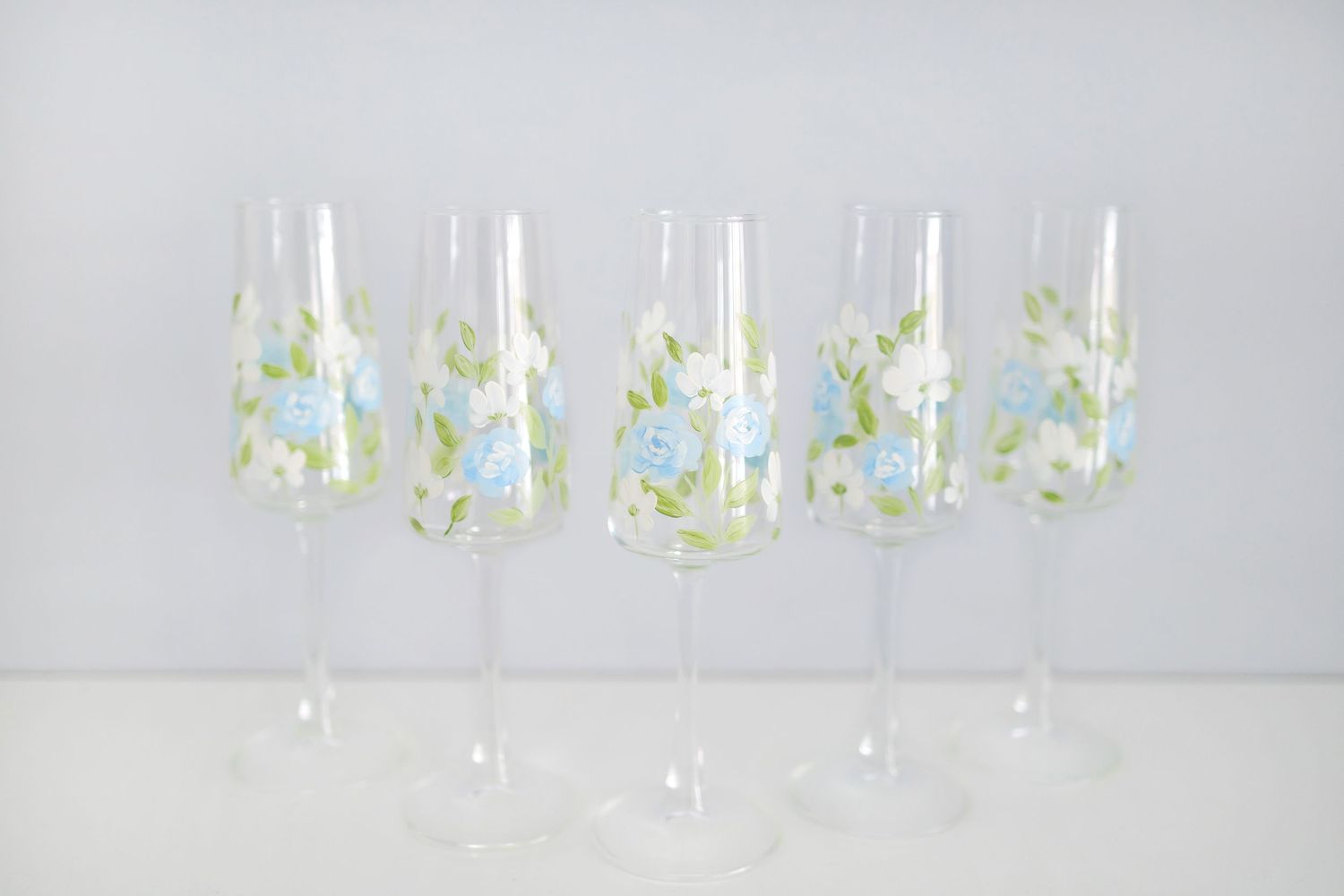 A row of wine glasses filled with clear liquid against a light gray background creates an elegant display pattern.