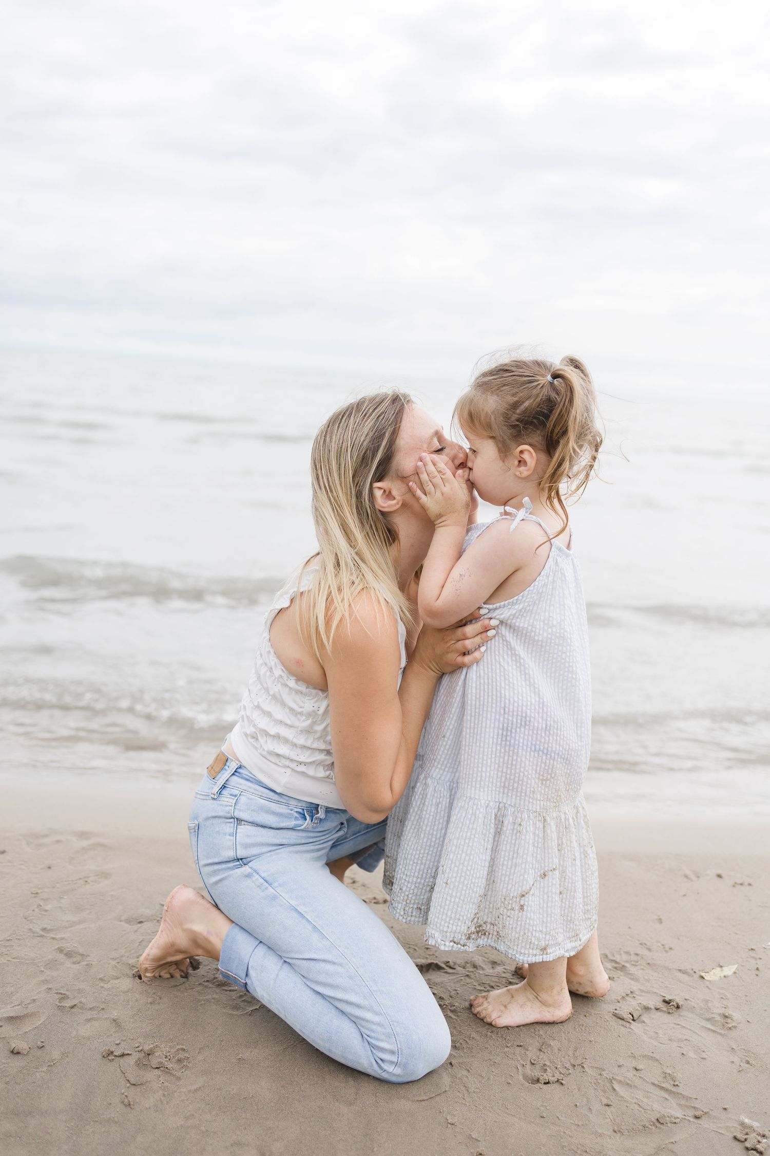 A tender moment shared between parent and child on a cloudy beach.