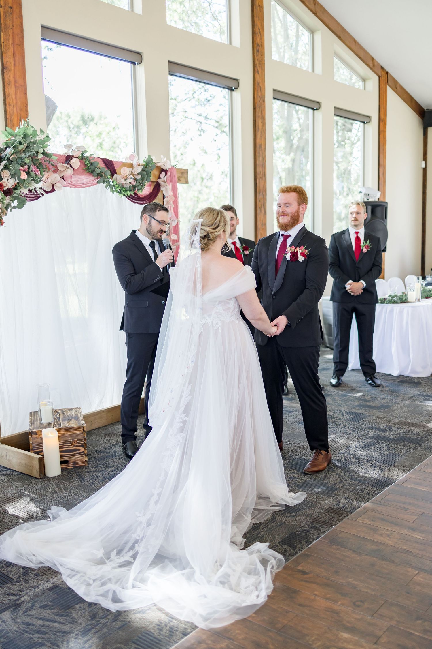 Wedding couple spins and dances in an elegant venue with large windows and wooden beams.