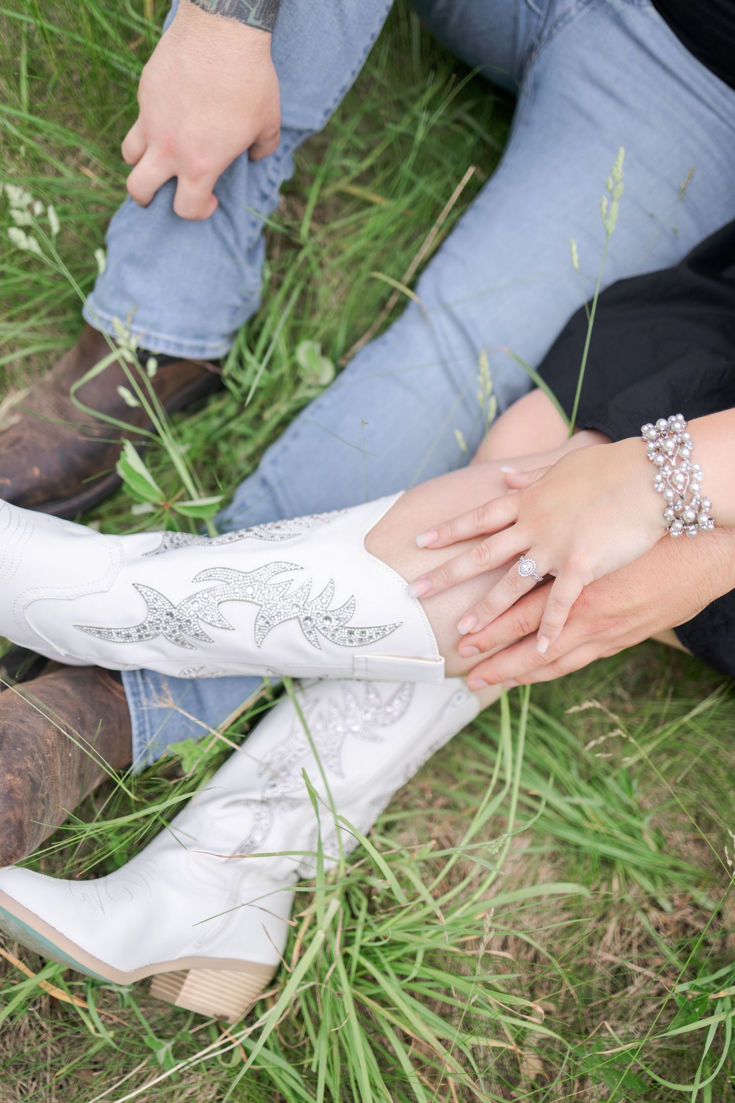Close-up shot of decorated white boots with floral designs against grass.