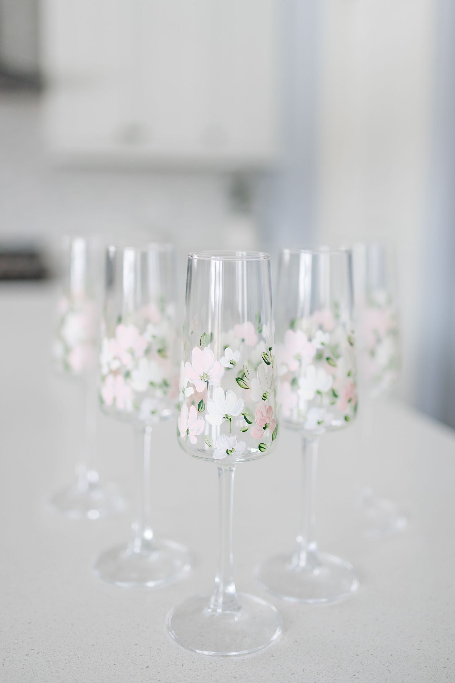 Delicate wine glasses adorned with soft pink and white floral decorations arranged in an elegant display.