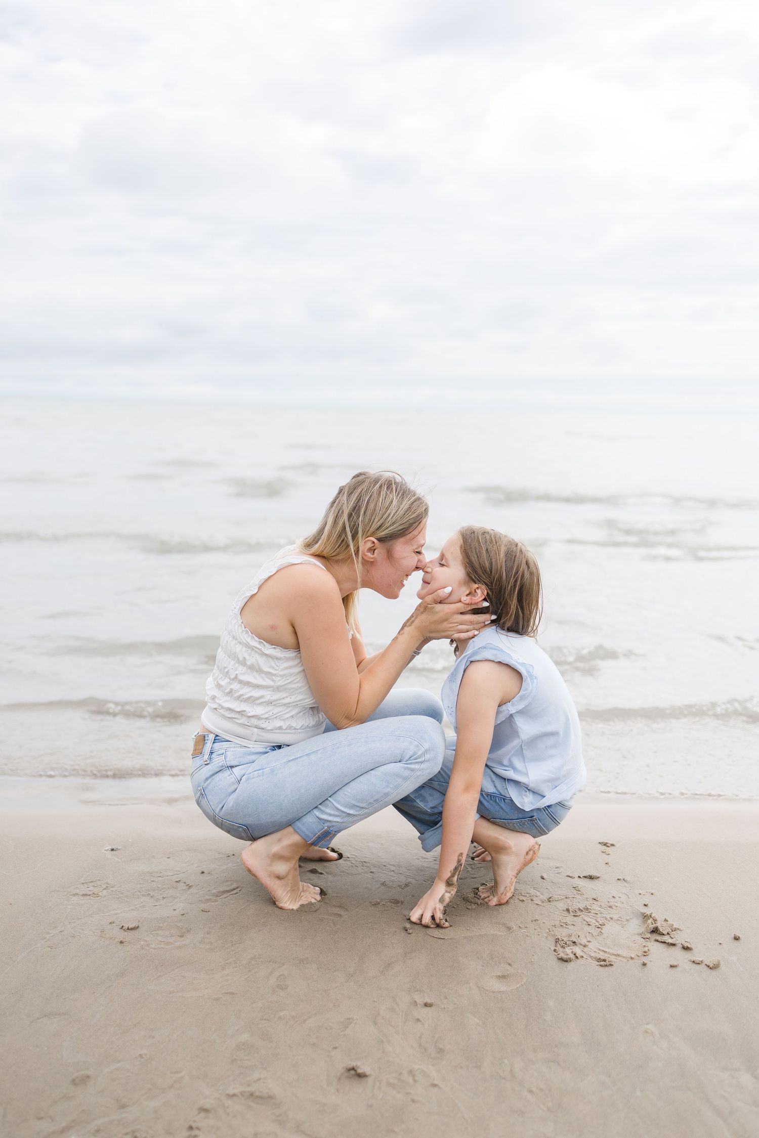 Mother and child sharing a playful moment on the sandy beach.