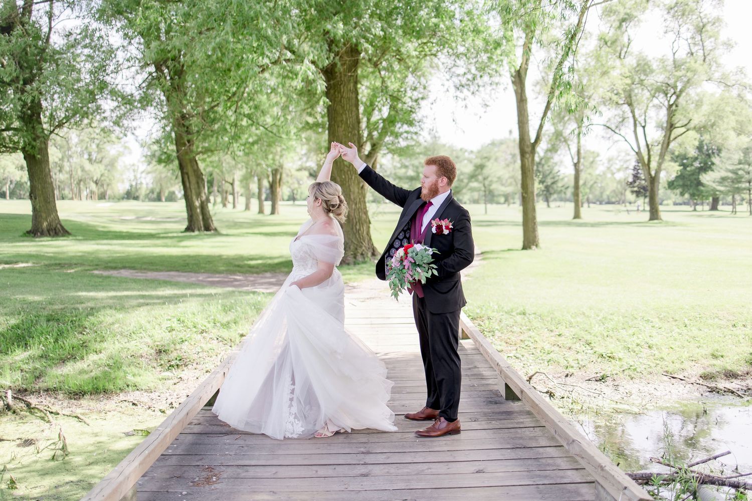 Wedding couple shares romantic moments on rustic wooden bridge in park.